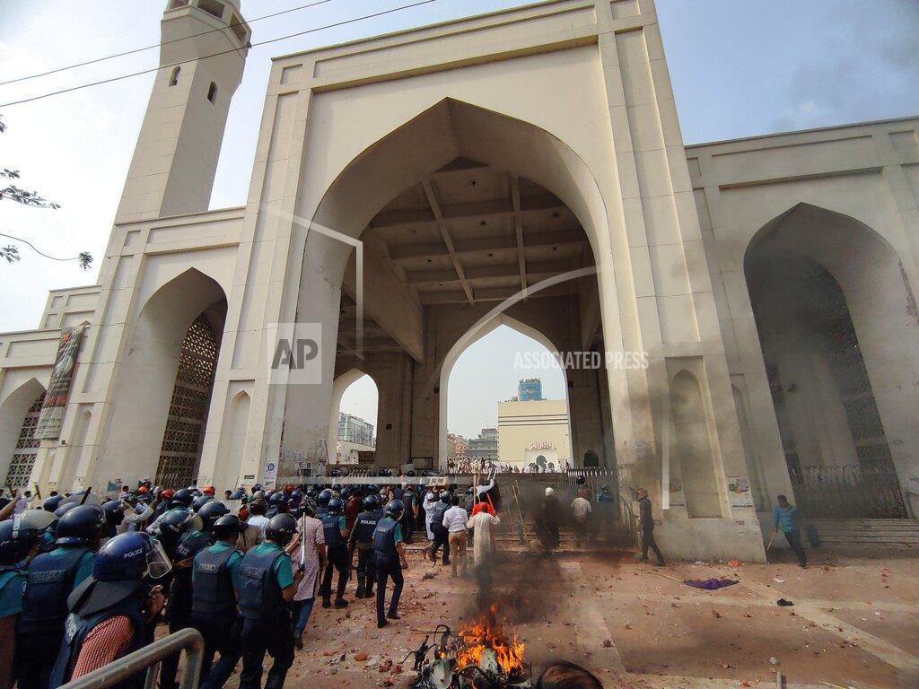 Mahmud Hossain Opu Security officers arrive as two factions of protestors clash after Friday prayers at Baitul Mokarram mosque in Dhaka, Bangladesh, Friday, March 26, 2021. Witnesses said violent clashes broke out after one faction of protesters began waving their shoes as a sign of disrespect to Indian Prime Minister Narendra Modi, and another group tried to stop them. Local media said the protesters who tried to stop the shoe-waving are aligned with the ruling Awami League party. The party criticized the other protest faction for attempting to create chaos in the country during Modi’s visit. (AP Photo/Mahmud Hossain Opu)