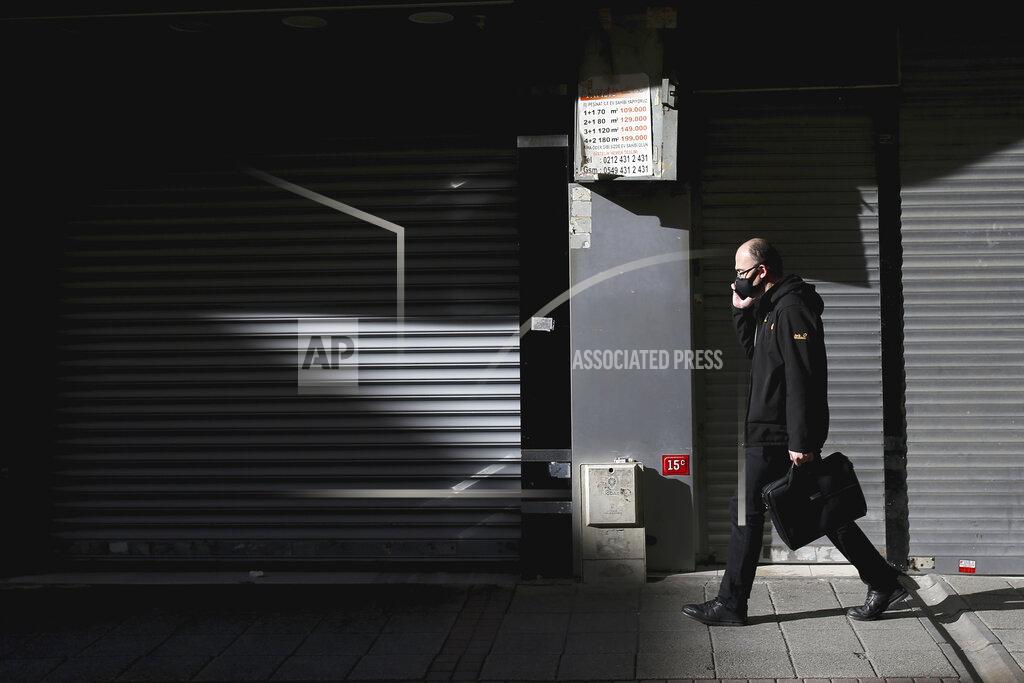 Emrah Gurel Backdroped by closed shops, a man, wearing a mask as preventive measures against the spread of the coronavirus, walks at Eminonu Bazaar in Istanbul, Friday, April 17, 2020, just hours before the start of a two-day curfew declared by Turkey's goverrnment in an attempt to control the spread of coronavirus. (AP Photo/Emrah Gurel)