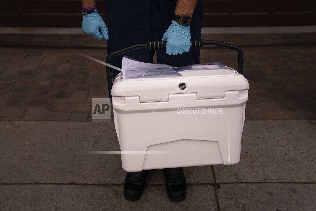 Jae C. Hong Torrance firefighter Trevor Borello carries a cooler containing the Pfizer COVID-19 vaccine to inoculate two sisters who have muscular dystrophy, Wednesday, May 12, 2021, in Torrance, Calif. Teamed up with the Torrance Fire Department, Torrance Memorial Medical Center started inoculating people at home in March, identifying people through a city hotline, county health department, senior centers and doctor's offices, said Mei Tsai, the pharmacist who coordinates the program. (AP Photo/Jae C. Hong)