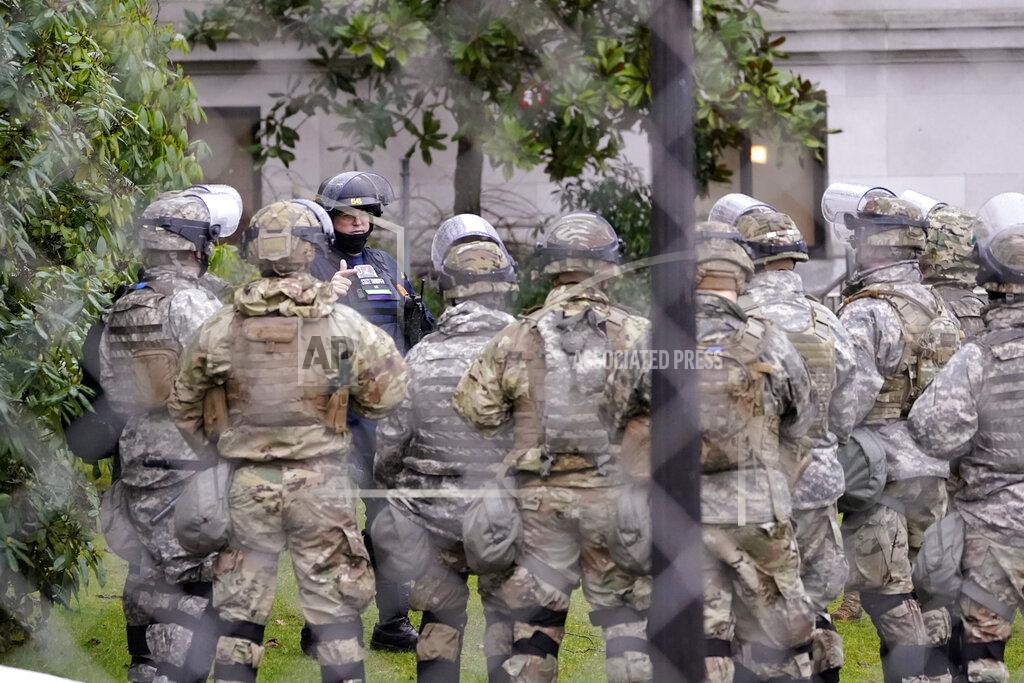 Ted S. Warren A Washington State Patrol trooper talks with members of the Washington National Guard inside a fence surrounding the Capitol in anticipation of protests Monday, Jan. 11, 2021, in Olympia, Wash. State capitols across the country are under heightened security after the siege of the U.S. Capitol last week. (AP Photo/Ted S. Warren)