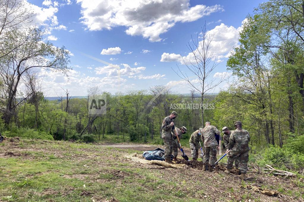 Julie Carr Smyth Members of the Ohio National Guard plant one of the trees at the dedication of Ohio's COVID-19 Pandemic Memorial Grove at Great Seal State Park near Chillicothe, Ohio., April 30, 2021. The country has begun finding ways to remember the more than 600,000 Americans who have died from the coronavirus, but the process is fraught compared to past memorial drives because of the politics. (AP Photo/Julie Carr Smyth)