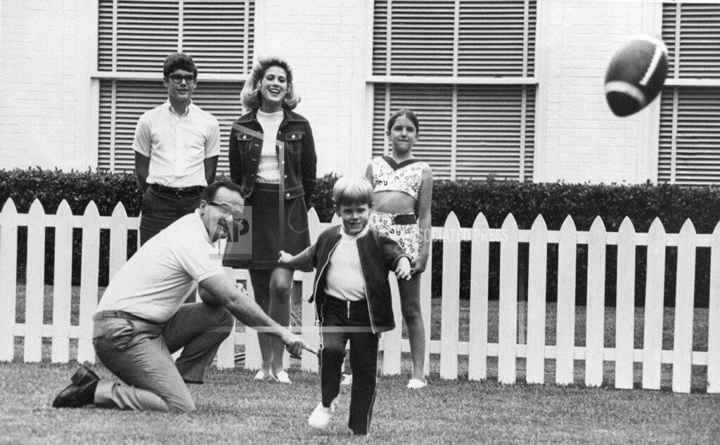 Anonymous FILE - In this June 1, 1970, file photo, Kansas City Chiefs owner Lamar Hunt watches after holding the ball for his son, Clark, 5, to kick in the family backyard in Dallas. Behind them is Hunt's children by a former marriage, Lamar Jr. 13, left, and Sharon, 12, right. His wife Norma is at center rear. Lamar Hunt was a champion of Black rights during the Civil Rights era of the 1960s. He grew up in conservative circles yet formed his own opinions of right and wrong. And when his football-loving son was born in 1965, those principles that Hunt instilled in his football franchise became instilled in Clark, who years later would take succeed him as chairman of the Chiefs. (AP Photo/File)