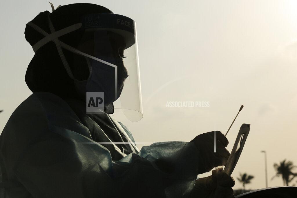 Saudi health worker, Wedad Modaifen collects a swab sample for a polymerase chain reaction (PCR) test at drive-through testing center, at King Abdulaziz University in Jiddah, Saudi Arabia Wednesday, Feb. 3, 2021. In Saudi Arabia, where authorities already have banned travel to the kingdom from 20 countries including the U.S., officials ordered all weddings and parties suspended. It closed down all shopping malls, gyms and other locations for 10 days, as well as indoor dining. (AP Photo/Amr Nabil)