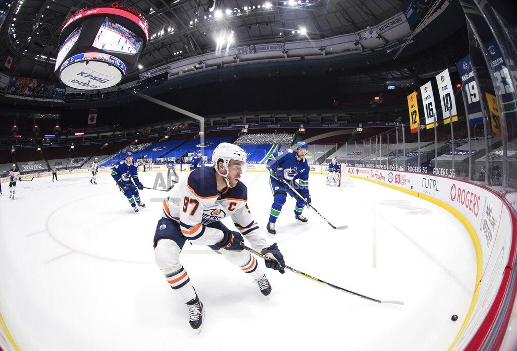 Darryl Dyck Edmonton Oilers' Connor McDavid (97) skates after the puck while being watched by Vancouver Canucks' Alexander Edler (23), of Sweden, during the first period of an NHL hockey game, Monday, May 3, 2021, in Vancouver, British Columbia. (Darryl Dyck/The Canadian Press via AP)