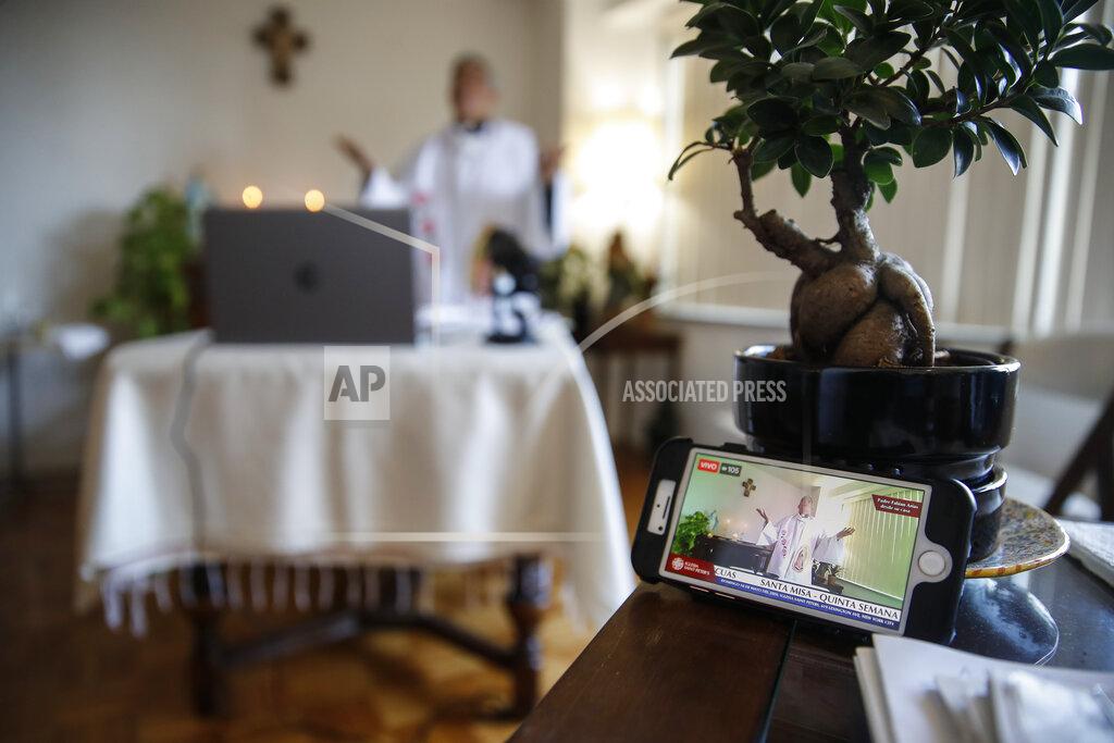John Minchillo Fabian Arias, a Lutheran pastor with Saint Peter's Church in Manhattan, is displayed on a cellular phone used to monitor his livestream Sunday service at his home, Sunday, May 10, 2020, in the Bronx borough of New York. (AP Photo/John Minchillo)