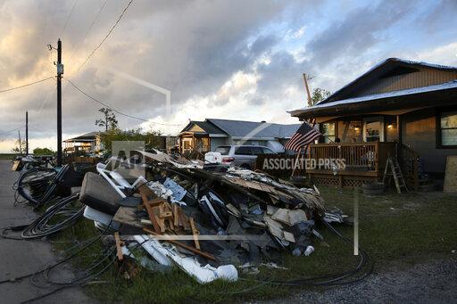 FILE - Debris and electrical wires are piled up in a front yard in Chauvin, La., on Sept. 27, 2021. In the aftermath of Hurricane Ida, Louisiana lawmakers said Wednesday, Dec. 1, 2021 they are seeing slow responses to damage claims, constant switch-ups of insurance adjusters assessing the destruction and low payment offers forcing people unnecessarily into litigation to get a fair deal. (AP Photo/Jessie Wardarski)