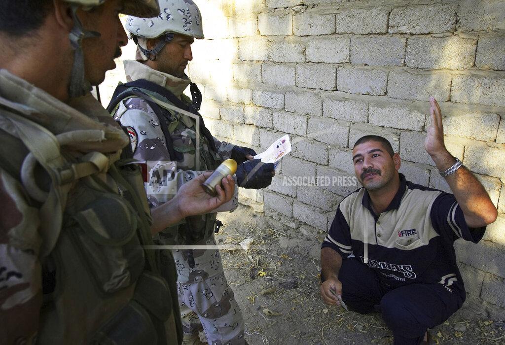 Jacob Silberberg FILE—This file photo from Aug. 6, 2005 shows Iraqi soldiers working with Lima Company of the U.S. Marines 3rd Battalion, 25th Regimen from Ohio, question a man they think might be involved in the killing of U.S. Marines earlier in the week, in Parwana, near Haditha, Iraq. Days before, a nearby roadside bomb killed 14 Marines, many from Lima Company, and a civilian interpreter on August 3, 2005. Some survivors and families of those killed had planned a 15-year reunion this weekend, but it had to be canceled amid restrictions for the COVID-19 pandemic. (AP Photo/Jacob Silberberg, File)