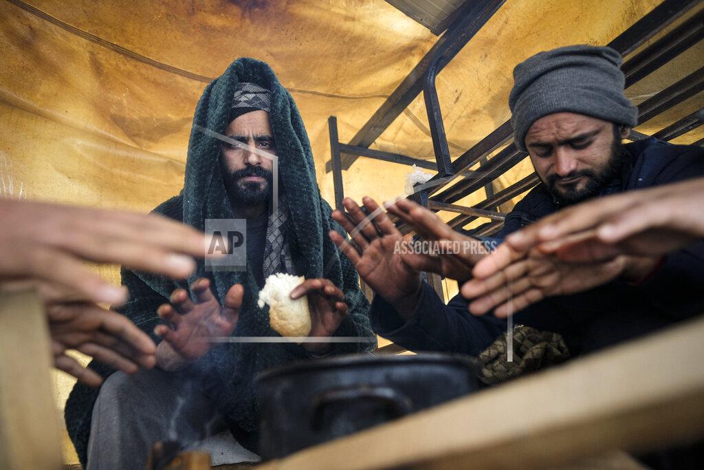 Kemal Softic Migrants warm their hands above a fire at the Lipa camp, outside Bihac, Bosnia, Monday, Jan. 11, 2021. Aid workers say migrants staying at a camp in northwestern Bosnia have complained or respiratory and skin diseases after spending days in make-shift tents and containers amid freezing weather and snow blizzards. Most of the hundreds of migrants at the Lipa facility near Bosnia's border with Croatia on Monday have been accommodated in heated military tents following days of uncertainty after a fire gutted most of the camp on Dec. 23. (AP Photo/Kemal Softic)