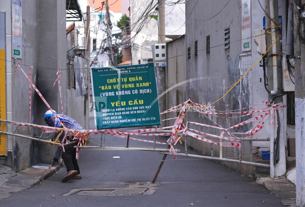 Hau Dinh A man breaches through a barricade to get in an alley in Vung Tau, Vietnam, Monday, Sept. 20, 2021. The roadblocks and barricades make the streets of this southern Vietnamese city look like they did during the war that ended almost 50 years ago. But this time, the battle is being fought against the rampaging coronavirus.(AP Photo/Hau Dinh)