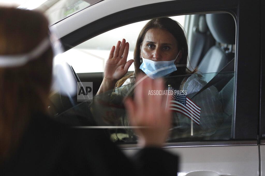 Carlos Osorio FILE- In this June 26, 2020, file photo, U.S. District Judge Laurie Michelson, left, administers the oath of citizenship to Hala Baqtar during a drive-thru naturalization service in a parking structure at the U.S. Citizenship and Immigration Services headquarters on Detroit's east side. U.S. Citizenship and Immigration Services has transformed under President Donald Trump to emphasize fraud detection, enforcement and vetting, which has delayed processing and contributed to severe fiscal problems. Its revamp came as the administration sought to cut legal immigration by making it more dependent on employment skills and wealth tests. (AP Photo/Carlos Osorio, FILE)