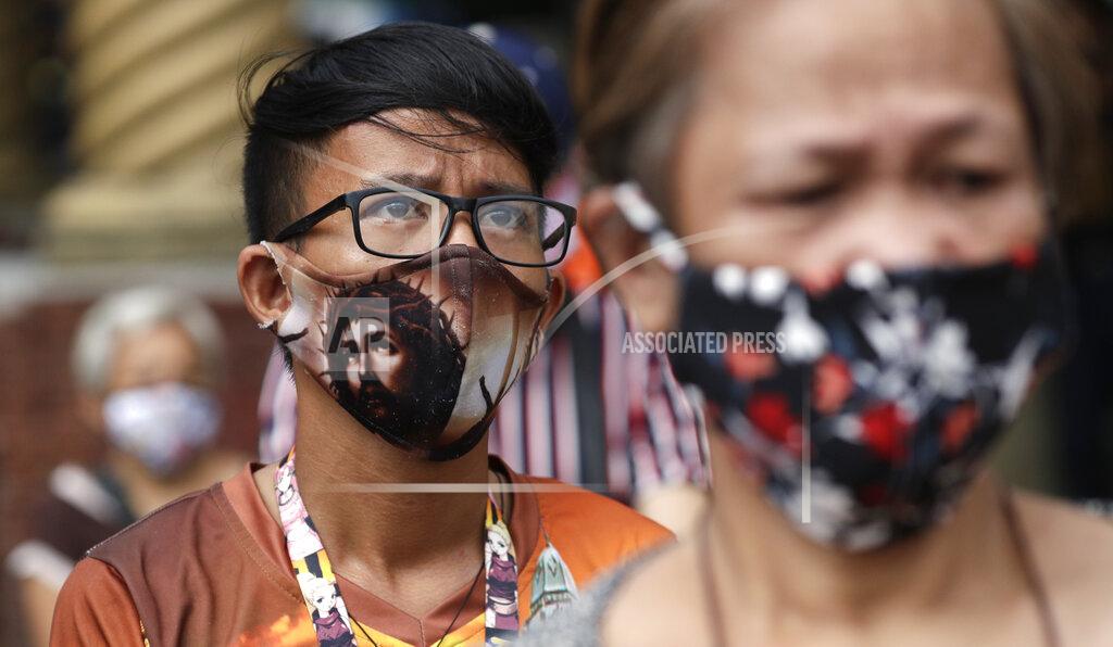 Aaron Favila A devotee wearing a protective mask bearing the face of Jesus Christ waits outside the Minor Basilica of the Black Nazarene, popularly known as Quiapo church, as it slowly reopens its doors in downtown Manila, Philippines on Friday, June 5, 2020. President Rodrigo Duterte has expressed relief that "Filipinos are really law-abiding" and that the Philippines was not going through riots like America which would make coronavirus quarantine enforcement formidable. (AP Photo/Aaron Favila)
