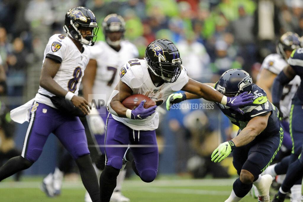 Baltimore Ravens running back Mark Ingram (21) fends off Seattle Seahawks linebacker Mychal Kendricks, right, as Ravens quarterback Lamar Jackson (8) looks on during the second half of an NFL football game, Sunday, Oct. 20, 2019, in Seattle. (AP Photo/John Froschauer)