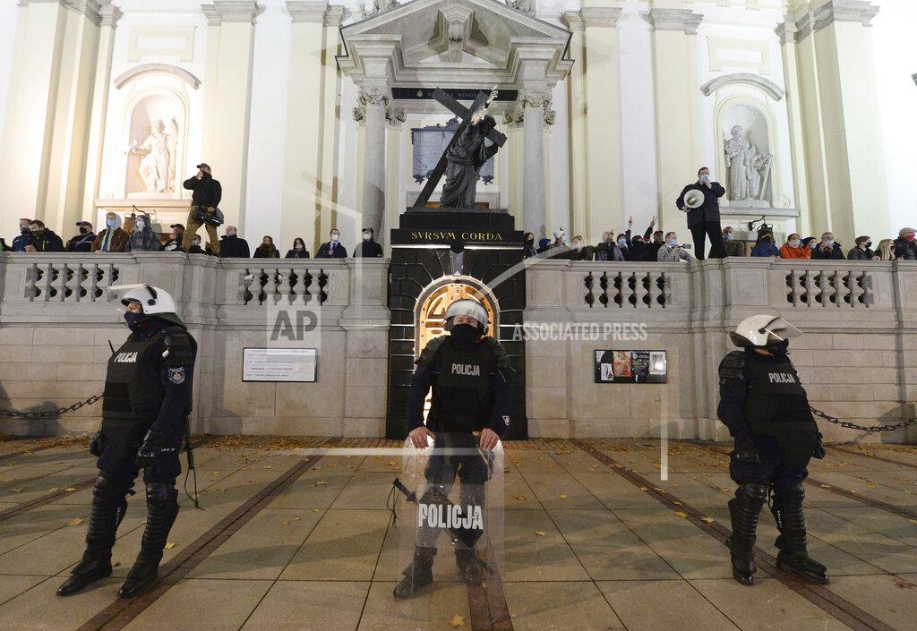 Czarek Sokolowski Members of a far-right organization stand guard in front of the Holy Cross Church, fronted by a row of police officers, in Warsaw, Poland, Wednesday Oct. 28, 2020. The far-right group members vowed to defend churches after protesters angry over an abortion ban disrupted Masses and spray-painted churches last Sunday. (AP Photo/Czarek Sokolowski)