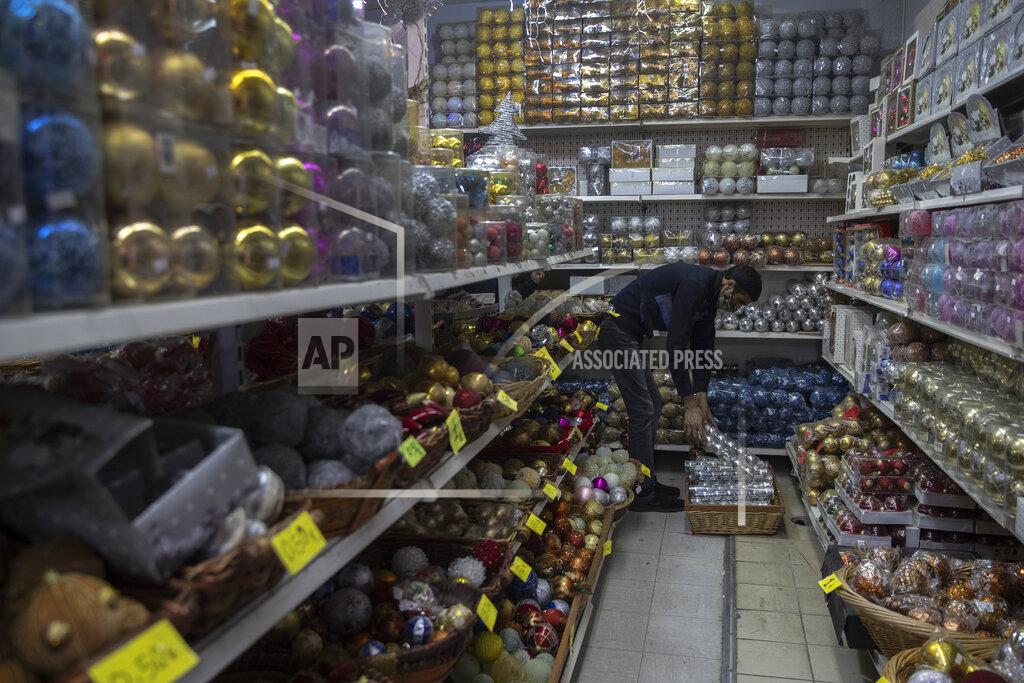 A worker places Christmas balls on shelves inside a shop , in central Athens, on Monday, Dec. 7, 2020. Despite a significant drop in cases over the past week, authorities have extended the countrywide lockdown to Dec. 14, but have allowed certain shops, including those selling Christmas-related merchandise, to open from Monday. (AP Photo/Petros Giannakouris)