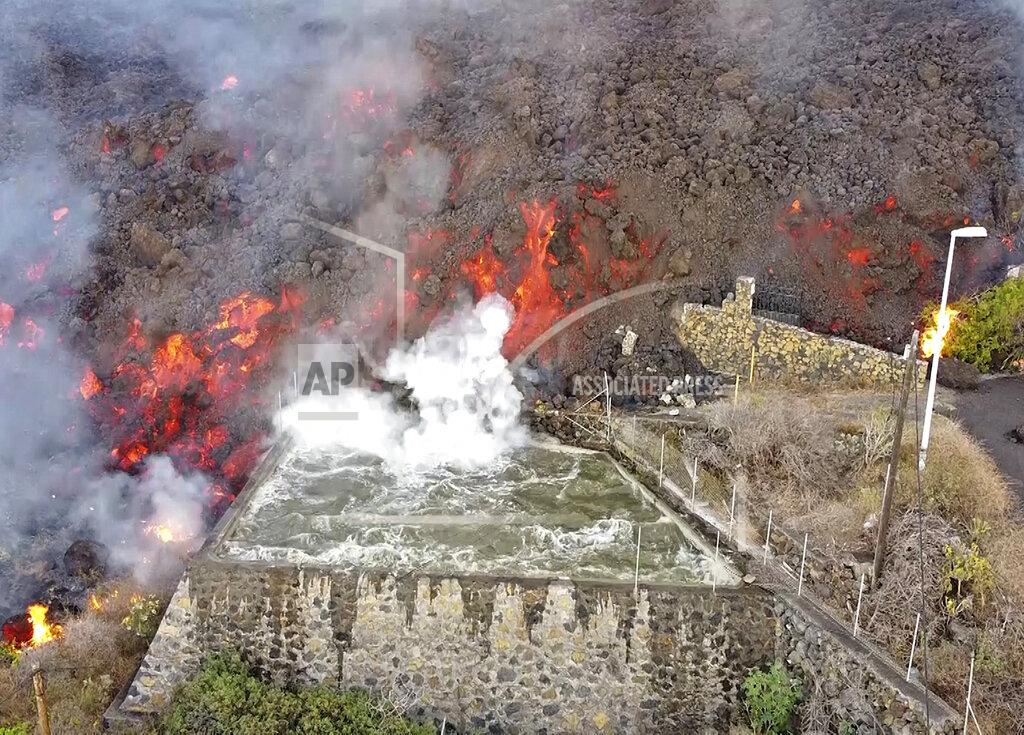 Uncredited FILE - In this Monday Sept. 20, 2021 file photo, hot lava reaches a balsa normally used for for irrigation after an eruption of a volcano on the island of La Palma in the Canaries, Spain. A long-dormant volcano on a small Spanish island in the Atlantic Ocean erupted on Sunday Sept. 19, 2021, forcing the evacuation of thousands of people. Huge plumes of black-and-white smoke shot out from a volcanic ridge where scientists had been monitoring the accumulation of molten lava below the surface. (Europa Press via AP, File)