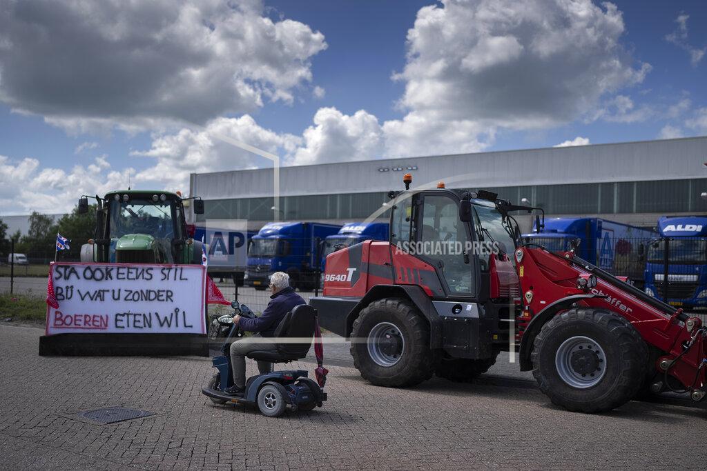Peter Dejong A man passes a tractor with a sign reading "Think What You Want to Eat Without Famers" at a blockade outside a distribution center for supermarket chain Aldi in the town of Drachten, northern Netherlands, Monday, July 4, 2022. Dutch farmers angry at government plans to slash emissions used tractors and trucks Monday to blockade supermarket distribution centers, the latest actions in a summer of discontent in the country's lucrative agricultural sector. (AP Photo/Peter Dejong)