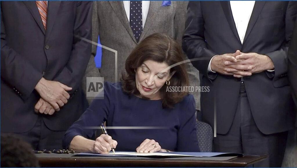 Uncredited In this image taken from video, New York Gov. Kathy Hochul signs an executive order during a news conference, Wednesday, May 18, 2022, in New York. New York would require state police to seek court orders to keep guns away from people who might pose a threat to themselves or others under a package of executive orders and gun control bills touted Wednesday by Hochul in the aftermath of a racist attack on a Buffalo supermarket. (Office of the Governor of New York via AP)