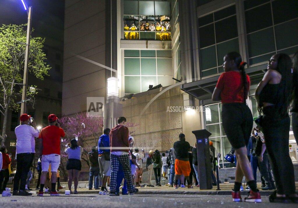 Colter Peterson Onlookers watch from the street as inmates chant and throw things from broken windows at the St. Louis Justice Center, known as the city jail, on Sunday, April 4, 2021. (Colter Peterson/St. Louis Post-Dispatch via AP)