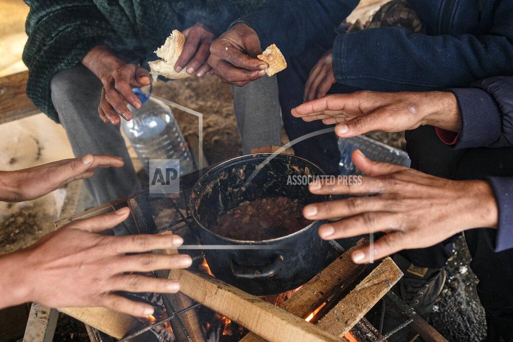 Kemal Softic Migrants warm their hands above a fire at the Lipa camp, outside Bihac, Bosnia, Monday, Jan. 11, 2021. Aid workers say migrants staying at a camp in northwestern Bosnia have complained or respiratory and skin diseases after spending days in make-shift tents and containers amid freezing weather and snow blizzards. Most of the hundreds of migrants at the Lipa facility near Bosnia's border with Croatia on Monday have been accommodated in heated military tents following days of uncertainty after a fire gutted most of the camp on Dec. 23. (AP Photo/Kemal Softic)