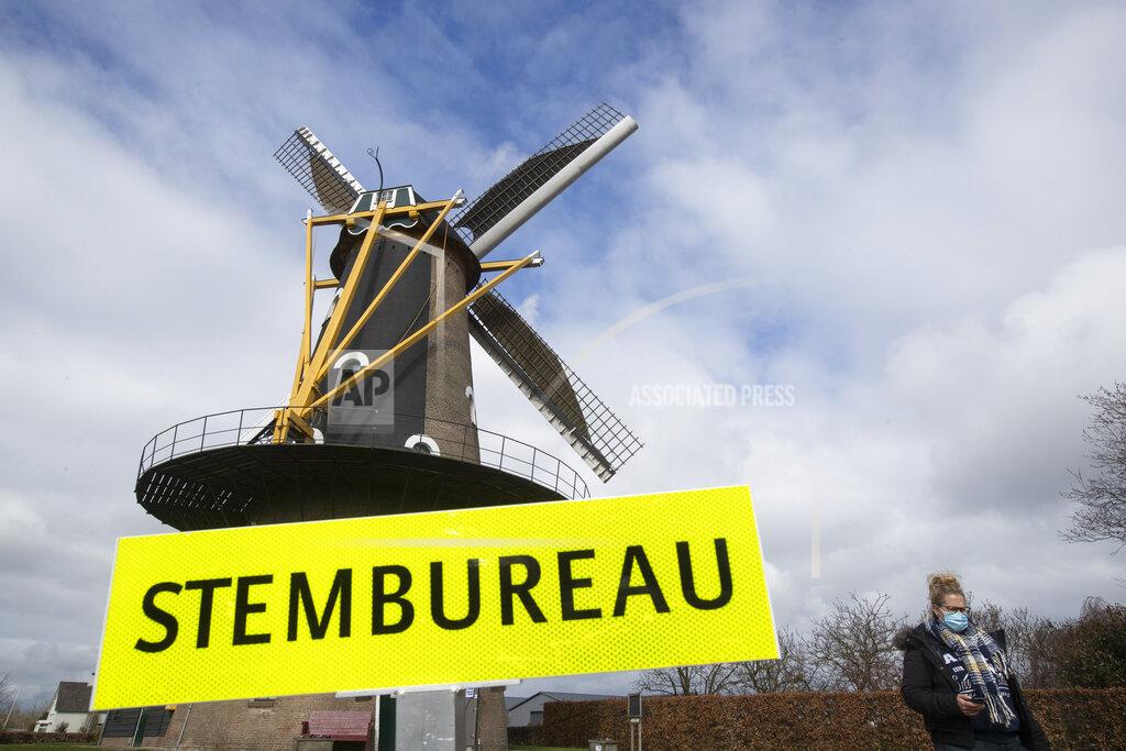 Peter Dejong A woman passes a sign reading "polling station" after casting her vote at windmill the Kerhovense Molen during general election in Oisterwijk, Netherlands, Wednesday, March 17, 2021. Polling stations have opened opened across the Netherlands from Monday in a general election that has been spread over three days to allow people to vote safely during the coronavirus pandemic. (AP Photo/Peter Dejong)