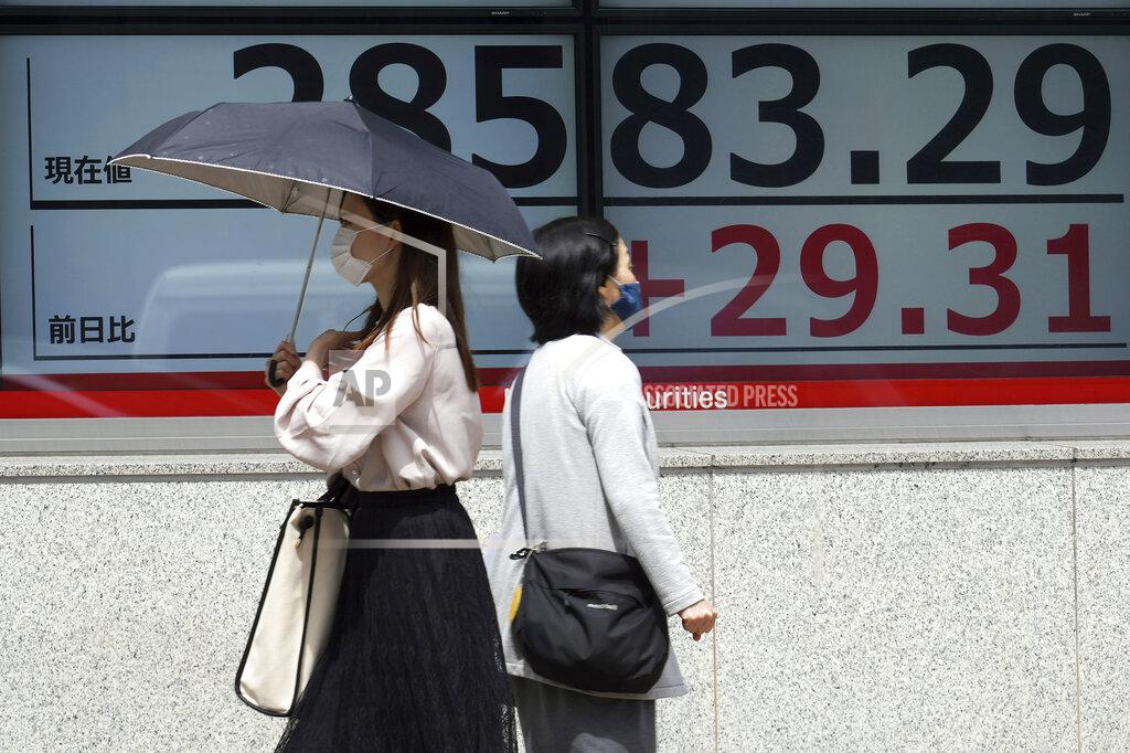 Eugene Hoshiko Women wearing protective masks walk in front of an electronic stock board showing Japan's Nikkei 225 index at a securities firm Wednesday, May 26, 2021, in Tokyo. Asian stock markets rose Wednesday as inflation fears eased and investors looked ahead to U.S. data that are expected to show economic growth accelerating. (AP Photo/Eugene Hoshiko)