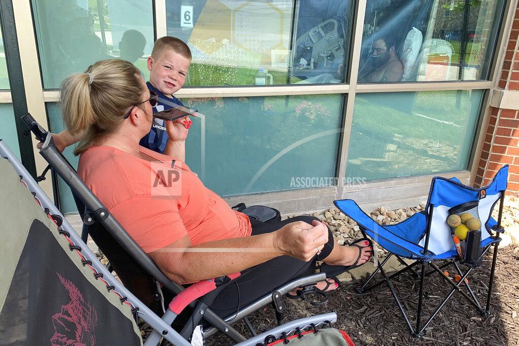 Sarah Blake Morgan Billie Barker, with her son Brody, 6, uses her cellphone to speak with her husband, Daryl, as he sits inside his room at Lake Regional Hospital in Osage Beach, Mo., on Monday, July 26, 2021. It was the 17th day the 31-year-old spent in the ICU battling COVID-19 as cases continue to rise across the state. (AP Photo/Sarah Blake Morgan)
