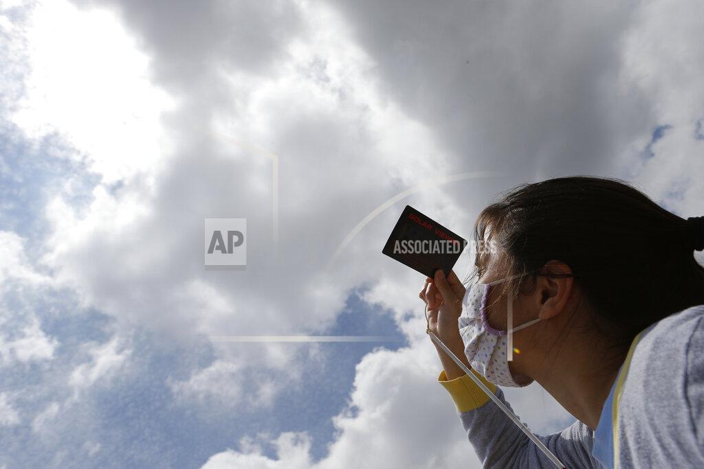 Cesar Olmedo Astronomy student Lorena Zalazar observes a partial solar eclipse from the boardwalk in Asuncion, Paraguay, Monday, Dec. 14, 2020. A total solar eclipse was visible from the northern Patagonia region of Argentina and from Araucania in Chile, and as a partial eclipse from the lower two-thirds of South America. (AP Photo/Cesar Olmedo)