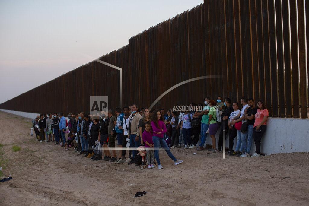 Dario Lopez-Mills A group of migrants stand next to the border wall as they wait to get taken away by the Border Patrol in Eagle Pass, Texas, Saturday, May 21, 2022. The Eagle Pass area has become increasingly a popular crossing corridor for migrants, especially those from outside Mexico and Central America, under Title 42 authority, which expels migrants without a chance to seek asylum on grounds of preventing the spread of COVID-19. (AP Photo/Dario Lopez-Mills)