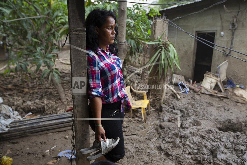Moises Castillo Nory Yamileth Hernandez stands at the property where she lived with 11 others, including her three teenage children, before it was flooded by last year's hurricanes Eta and Iota in San Pedro Sula, Honduras, Tuesday, Jan. 12, 2021. Hernández, 34, said she had joined the first big migrant caravan hoping to reach the U.S. in October 2018 but didn’t make it to Mexico before turning back, and is sure she will try again soon. (AP Photo/Moises Castillo)