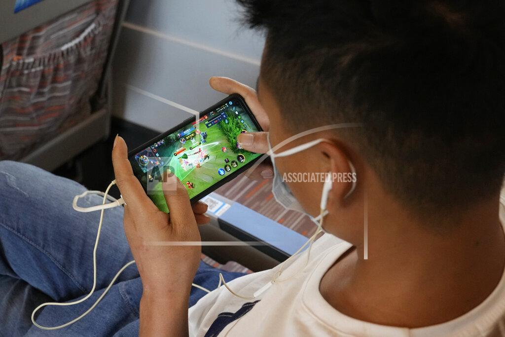 Ng Han Guan A man plays the popular Honor of Kings online game from Chinese gaming platform Tencent during a high speed train from Henan to Beijing Wednesday, Sept. 15, 2021. China has set new rules limiting the amount of time kids can spend playing online games. (AP Photo/Ng Han Guan)