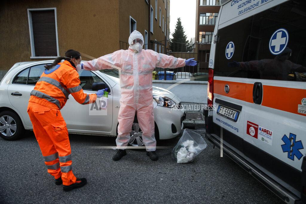 Luca Bruno Medical staffer Elisa Bonalumi sanitizes her colleague Ruggero Gariboldi after treating a suspected Covid patient inside the ambulance during their shift with the emergency White Cross in Monza, Italy, Friday, Nov. 20, 2020. The city of Monza north of Milan is best known for its Formula 1 racetrack. In 2020, it has been the ambulance service that has been doing most of the racing. Over three days that an Associated Press photographer traveled on night calls with an ambulance service, the Monza-Brianza province of some 875,000 bordering Milan added 2,500 new cases, part of Italy’s new epicenter in the Lombardy region. (AP Photo/Luca Bruno)