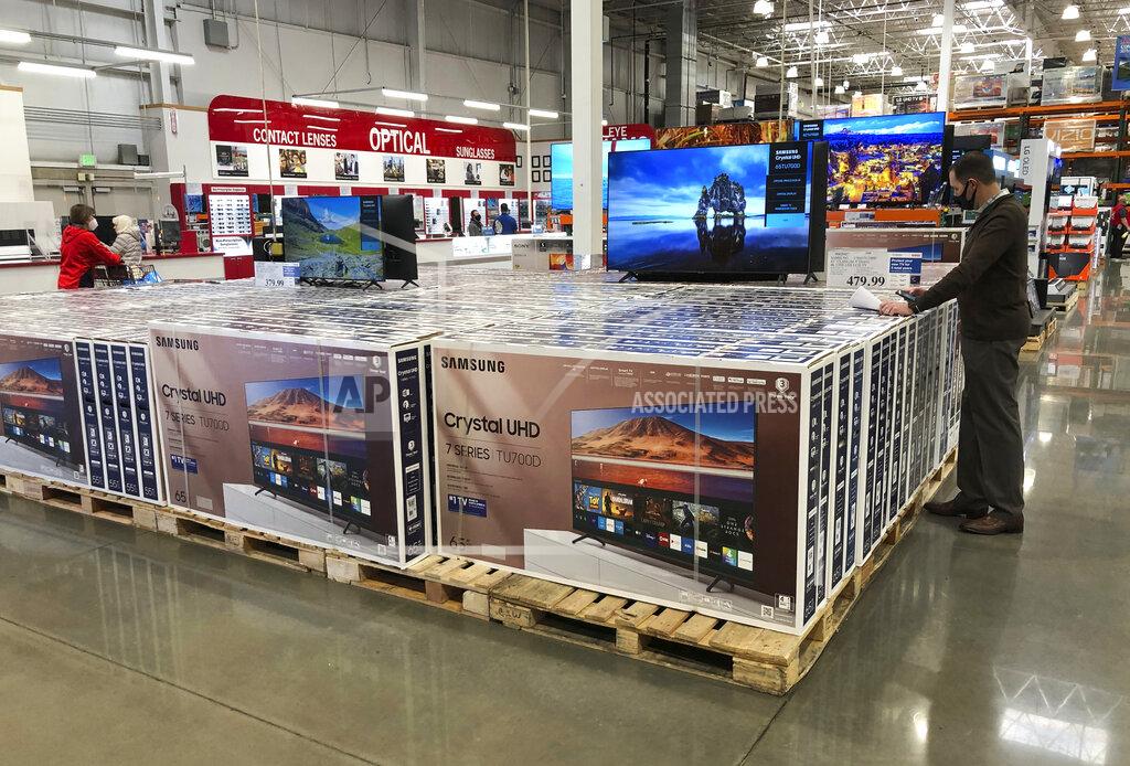 In this Nov. 10, 2020 photo, a shopper stands by a display of Samsung 65-inch televisions in a Costco warehouse in Sheridan, Colo. U.S. consumer confidence posted a gain in January, helped by a rise in expectations about the future. The Conference Board reported Tuesday, Jan. 26, 2021, that its consumer confidence index increased to 89.3, a rebound from December when it had fallen to a reading of 87.1. (AP Photo/David Zalubowski)