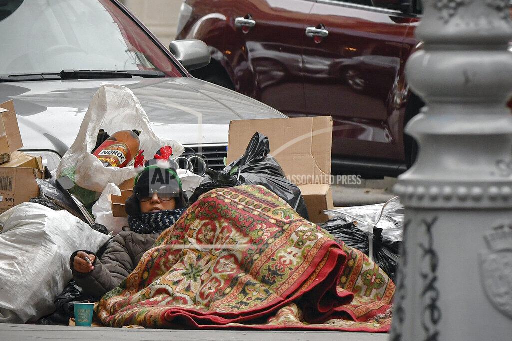 Andreea Alexandru A person lies on the pavement covered in a carpet downtown Bucharest, Romania, Thursday, Dec. 3, 2020. Romania will hold parliamentary elections on Sunday Dec. 6. (AP Photo/Andreea Alexandru)