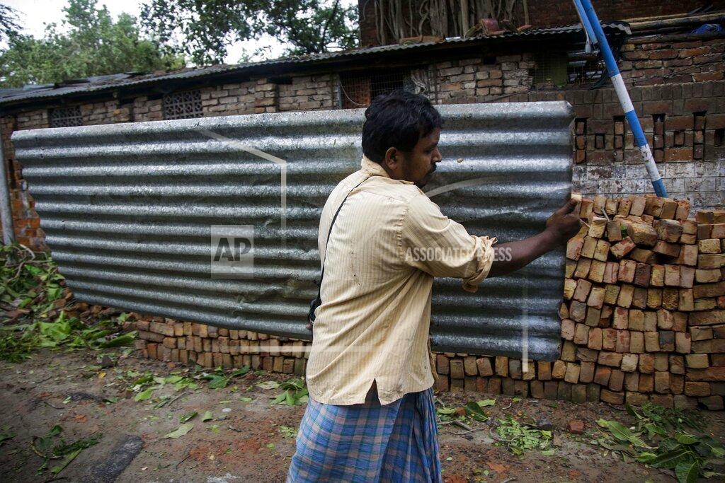 Bikas Das A shopkeeper carries a corrugated tin blown away from his shop when Cyclone Amphan hit the region in Kolkata, India, Thursday, May 21, 2020. A powerful cyclone ripped through densely populated coastal India and Bangladesh, blowing off roofs and whipping up waves that swallowed embankments and bridges and left entire villages without access to fresh water, electricity and communications. (AP Photo/Bikas Das)