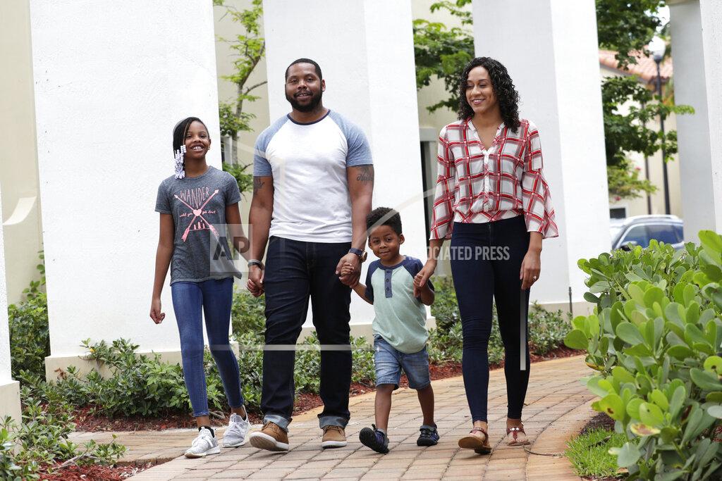 Lynne Sladky In this Tuesday, June 16, 2020 photo, D.J. Boldin, second from left, walks outside of their home with his children Madison, 10, left, and Dallas, 4, second from right, and his fiancee Sasha Jones in Miramar, Fla. Boldin is the football coach at Pahokee High School, a predominantly black school located alongside Lake Okeechobee in Florida. Recent events have given Boldin an opportunity to use his position to prepare his players for the challenges they will face when they leave the bubble that is their small town. (AP Photo/Lynne Sladky)