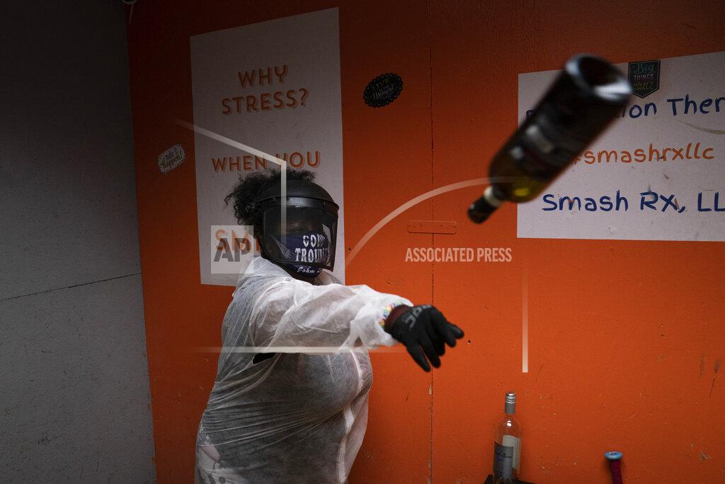 Jae C. Hong La Shaun Aaron, 43, throws a wine bottle into a wall during a session to help relieve stress at Smash RX LLC in Westlake Village, Calif., Friday, Feb. 5, 2021. Meditation, yoga, Pilates, they may be fine for some people. But after nearly a year in COVID-19 isolation, some people just want to grab a sledgehammer and smash everything in sight. Thankfully, for them there are now two "rage rooms" located in the Los Angeles suburb of Westlake Village, where they can do just that and not get in trouble. (AP Photo/Jae C. Hong)