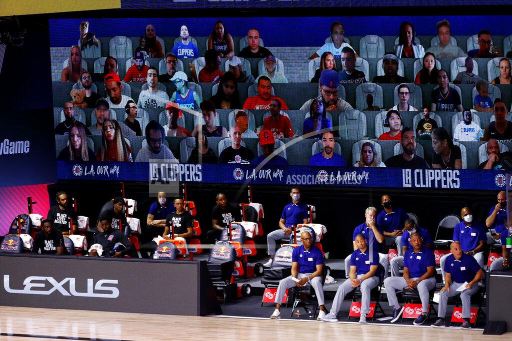 Kevin C. Cox FILE - This Tuesday, Aug. 4, 2020, file photo shows a view of the Los Angeles Clippers bench and fans on a screen during the first half of an NBA basketball game against the Phoenix Suns in Lake Buena Vista, Fla. The entire essence of sports as we know them changed in subtle, if fundamental, ways during the past 12 months because of restrictions on crowds. (Kevin C. Cox/Pool Photo via AP, File)
