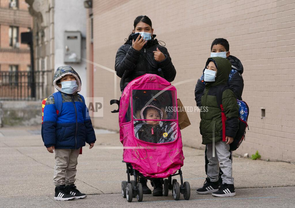 Mark Lennihan A woman and her children walk to P.S. 134 Henrietta Szold Elementary School, Monday, Dec. 7, 2020, in New York. Public schools reopened for in-school learning Monday after being closed since mid-November. (AP Photo/Mark Lennihan)