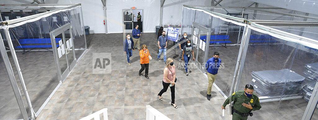 Randy Hoeft People touring the U.S. Border Patrol Yuma Sector, soft-sided processing facility, look at the pods inside one of four living areas at the facility during an open house, Tuesday, April 20, 2021, in Yuma, Ariz., in which the public was invited to see how the USBP will handle detained illegal immigrants who are apprehended while crossing the border into the United States from Mexico. The facility includes a laundry facility; multipurpose shower and changing area; an intake and medical area; processing area; 15 private phone rooms; and the four living areas, each divided into eight pods. (Randy Hoeft/The Yuma Sun via AP)