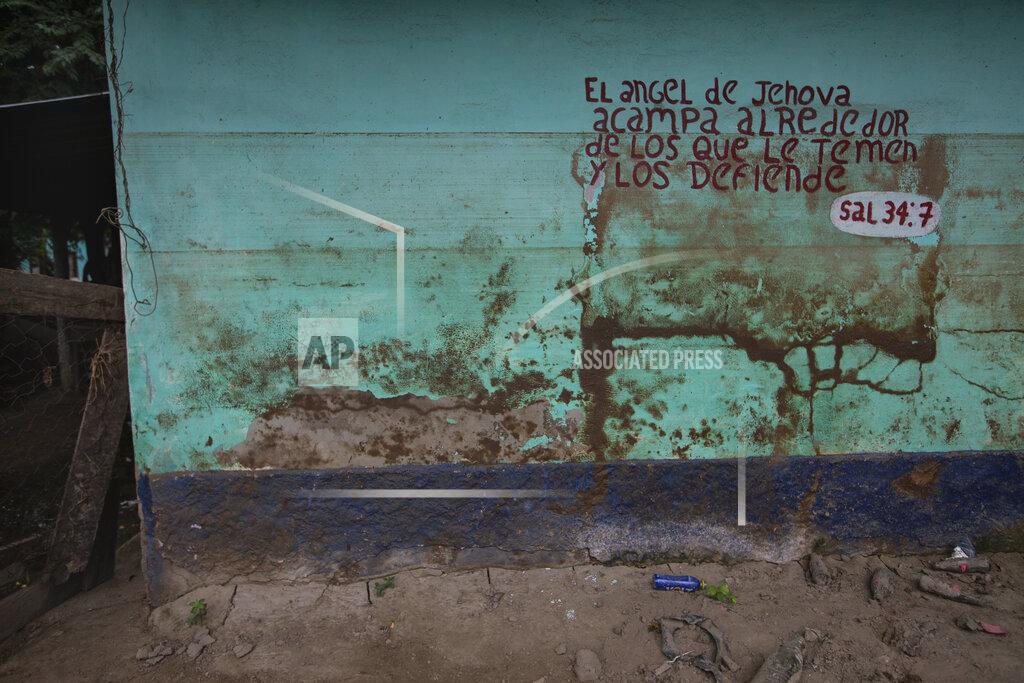 Moises Castillo Stains left by mud and water from last year's hurricanes Eta and Iota mark a wall decorated by a Bible passage in the Saviñon Cruz neighborhood of San Pedro Sula, Honduras, Tuesday, Jan. 12, 2021. The words say in Spanish "The angel of the Lord encamps around those who fear him, and he delivers them. Psalm 34:7" (AP Photo/Moises Castillo)