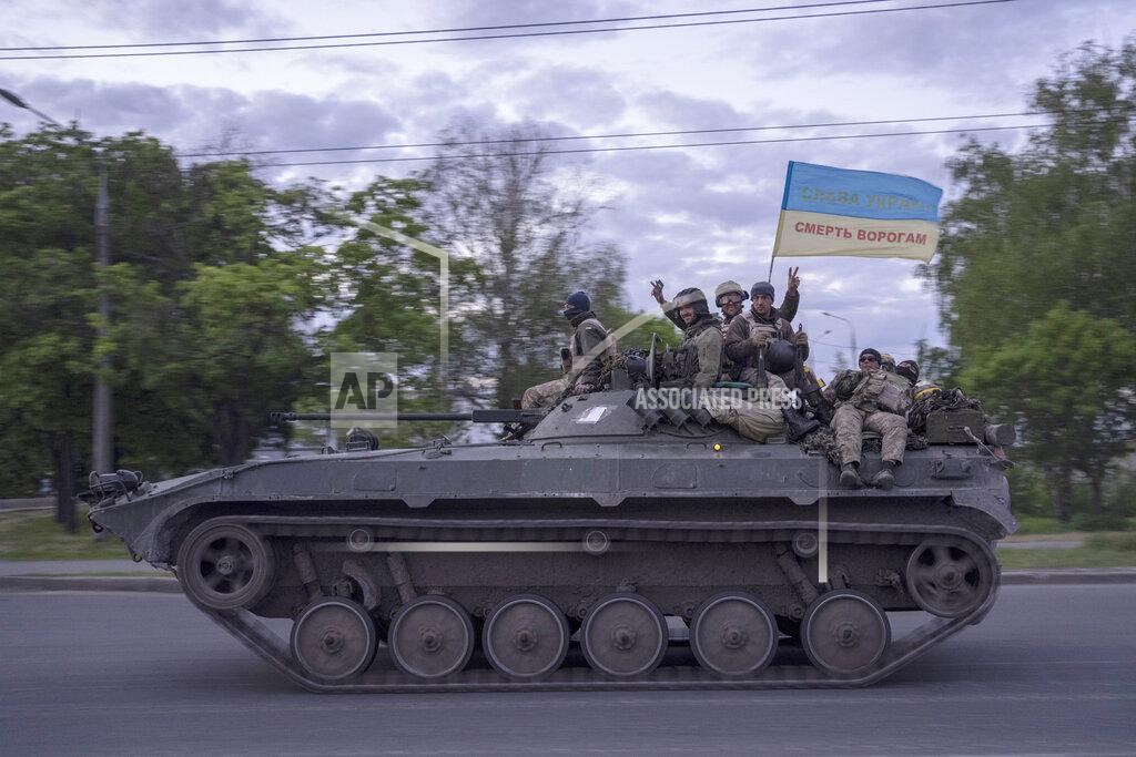Bernat Armangue Ukrainian serviceman wave a flag with writing reading in Ukrainian "Glory to Ukraine", top, and "Death to the enemies" as they ride atop of a tank in the Kharkiv region, eastern Ukraine, Monday, May 16, 2022. (AP Photo/Bernat Armangue)