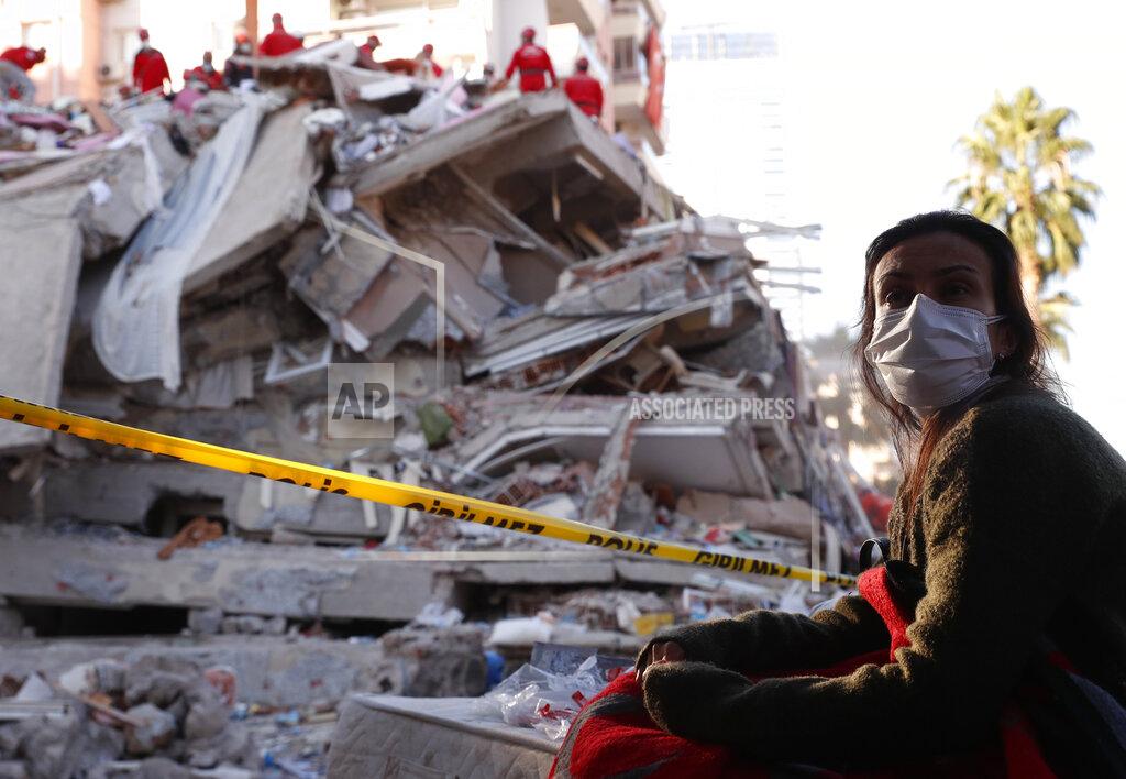 Darko Bandic A local resident, staying outdoors for fear of aftershocks, watches as members of rescue services search for survivors in the debris of a collapsed building in Izmir, Turkey, Saturday, Oct. 31, 2020. Rescue teams on Saturday ploughed through concrete blocs and debris of eight collapsed buildings in Turkey's third largest city in search of survivors of a powerful earthquake that struck Turkey's Aegean coast and north of the Greek island of Samos, killing dozens Hundreds of others were injured. (AP Photo/Darko Bandic)