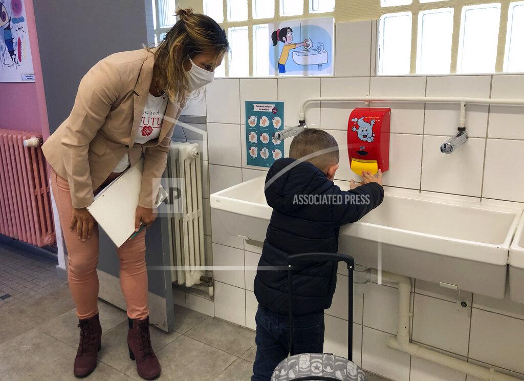 Jeffrey Schaeffer Teacher Lise Genrault looks at a schoolchild washing his hands at the Roissy-en-Brie elementary school, outside Paris, Tuesday, Sept.1, 2020. Millions of French children starting going back to class Tuesday despite a recent rise in virus infections, in a nationwide experiment aimed at bridging inequalities and reviving the economy. (AP Photo/Jeffrey Schaeffer)