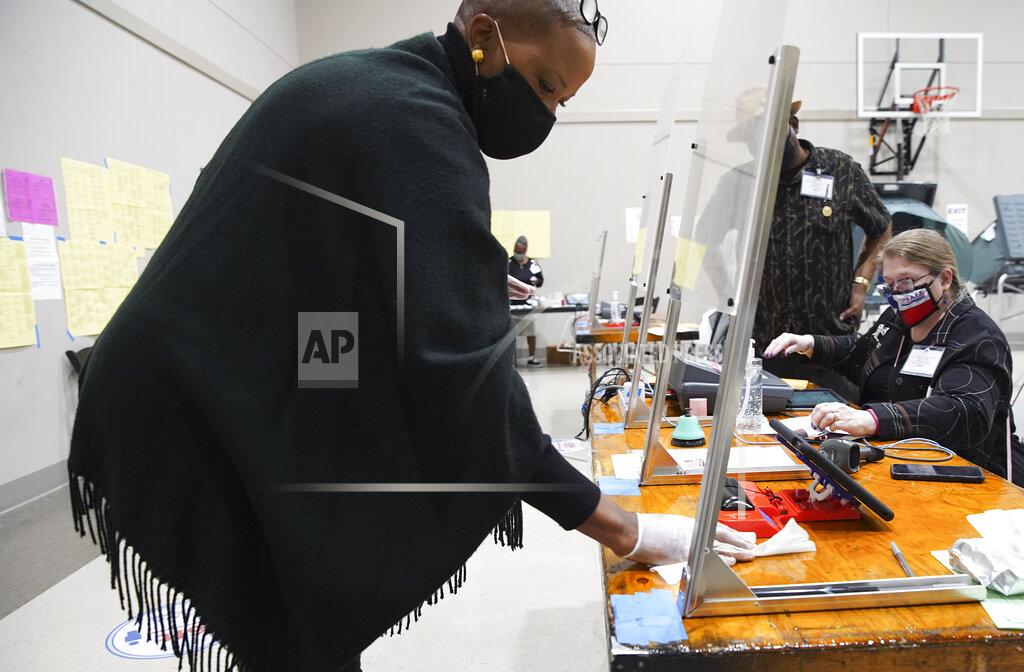 Elizabeth Conley A poll worker wipes down a station as the machines are closed for the day at Victory Houston polling station in Houston on Thursday, Oct. 29, 2020. The location was one of the Harris County's 24-hour locations, but had to close before midnight and then restart after midnight for the next day's results. ( Elizabeth Conley/Houston Chronicle via AP)