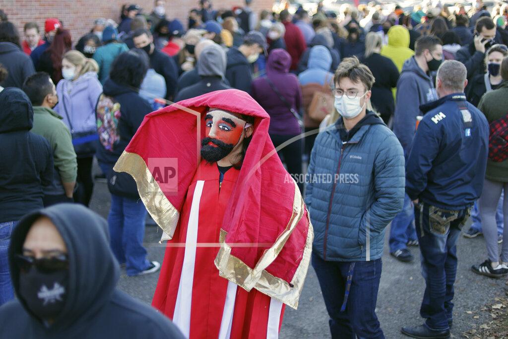 Nati Harnik Adam Fogerty wears a costume on Halloween, as he stands in line with others to vote early, at the Douglas County Election Commission office in Omaha, Neb., Saturday, Oct. 31, 2020. (AP Photo/Nati Harnik)