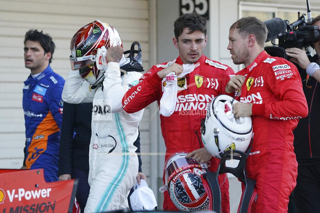Ferrari driver Sebastian Vettel of Germany, right, talks with teammate Charles Leclerc of Monaco as Mercedes driver Lewis Hamilton of Britain prepares to put off his helmet after the Japanese Formula One Grand Prix at Suzuka Circuit in Suzuka, central Japan, Sunday, Oct. 13, 2019. (AP Photo/Toru Hanai)