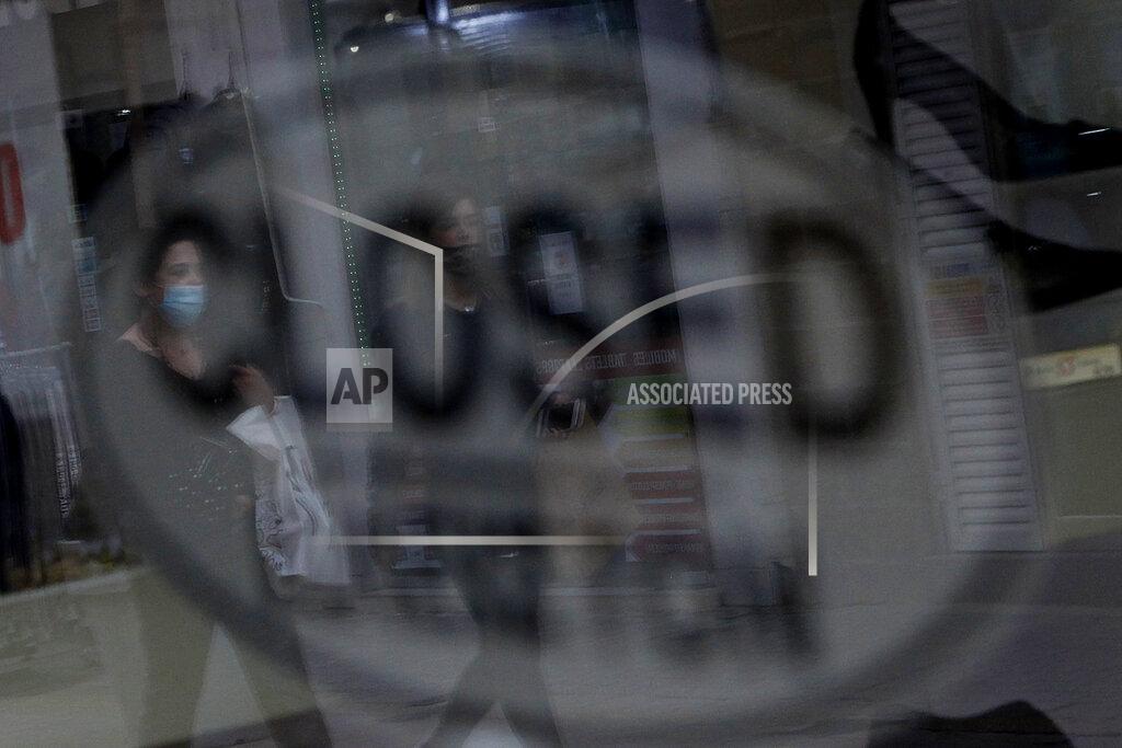 Petros Karadjias Women wearing face masks are reflected on the window of a closed shop, in central Nicosia, Friday, Jan. 8, 2021. Cyprus is returning to lockdown mode for the remainder of the month with daytime restrictions on movement and a shuttering of schools after the country's health minister conceded that a raft of tough measures already in place including a night-time curfew weren't enough to curtail the spread of the coronavirus. (AP Photo/Petros Karadjias)