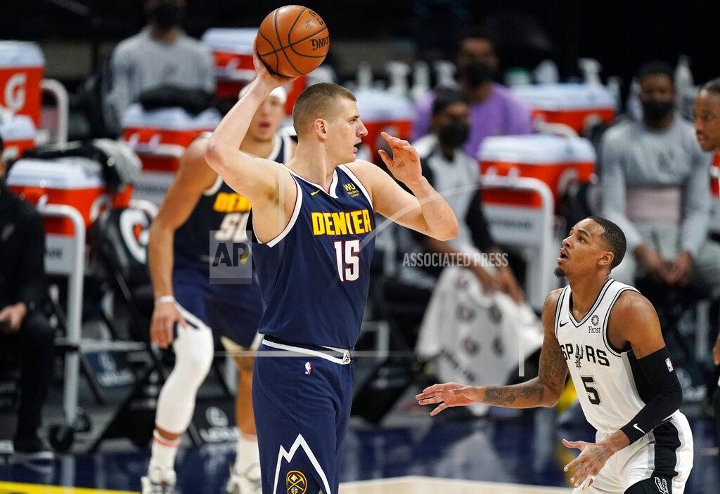 David Zalubowski Denver Nuggets center Nikola Jokic, front left, looks to pass the ball as San Antonio Spurs guard Dejounte Murray, right, defends in the first half of an NBA basketball game Friday, April 9, 2021, in Denver. (AP Photo/David Zalubowski)