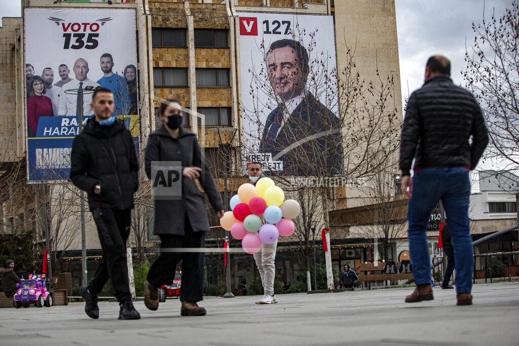 Visar Kryeziu Pedestrians walk past a man selling balloons in front of electoral poster with portrait of the candidate for the prime minister of "Self-Determination" party Albin Kurti, right, and candidate for president of Alliance for Future of Kosovo "AAK" Ramush Haradinaj in capital Pristina, Kosovo, on Wednesday, Feb. 10, 2021. Kosovo holds an early general election on upcoming Sunday Feb. 14, amid the coronavirus pandemic, economic downturn and stalled negotiations with wartime foe Serbia.(AP Photo/Visar Kryeziu)