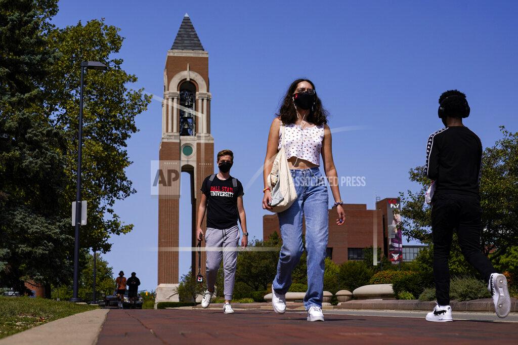 FILE - Masked students walk through the campus of Ball State University in Muncie, Ind., Thursday, Sept. 10, 2020. Colleges across the country are struggling to salvage the fall semester as campus coronavirus cases skyrocket and tensions with local health leaders flare. Schools have locked down dorms, imposed mask mandates, barred student fans from football games and toggled between online and in-person classes. (AP Photo/Michael Conroy)